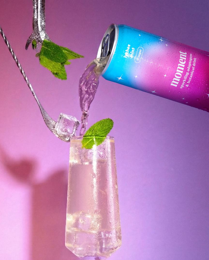A colorful can pouring drink with mint into a glass.