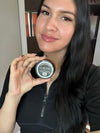 Person holding a small container, smiling at the camera.