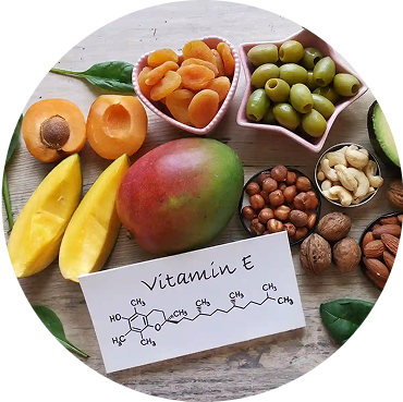 Assorted fruits, nuts, and a Vitamin E card on a wooden surface.