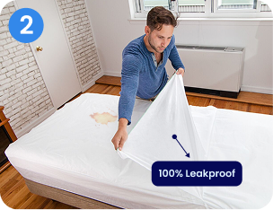 A man puts a white, 100% leakproof mattress protector over a stain on a mattress.
