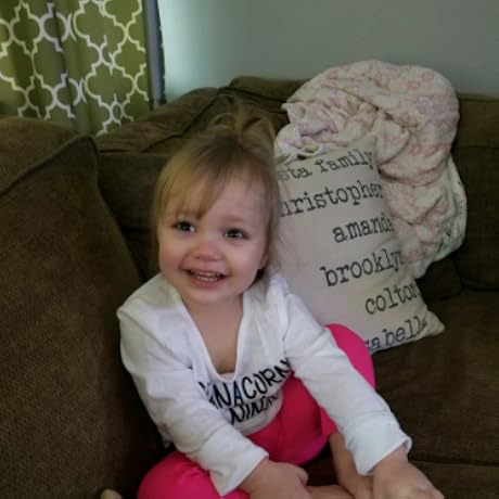 A smiling child sitting on a couch with a personalized pillow and blanket in the background.