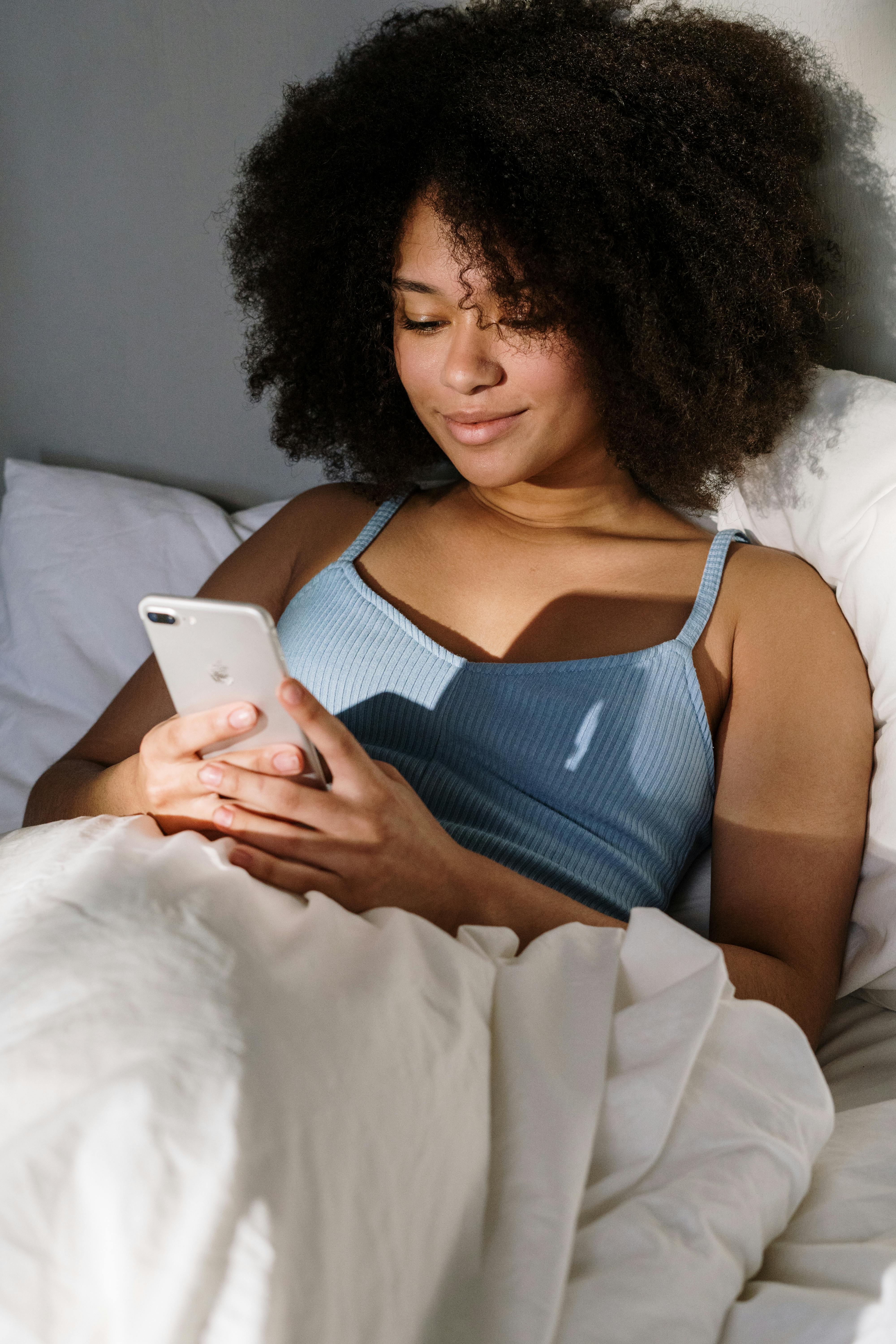 Person lying in bed, using a smartphone.