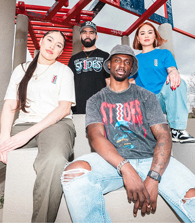 Four individuals in casual clothing posing outdoors under a red structure.