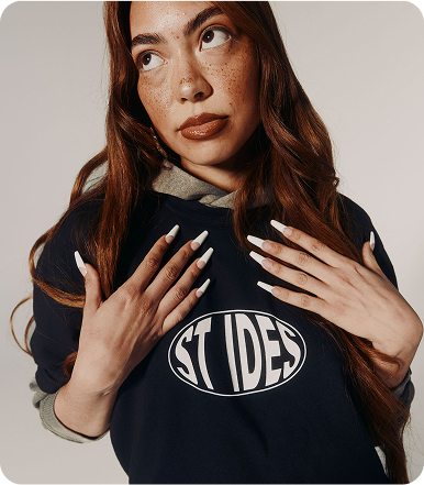 Person with long nails wearing a 'ST IDES' shirt, looking upward.