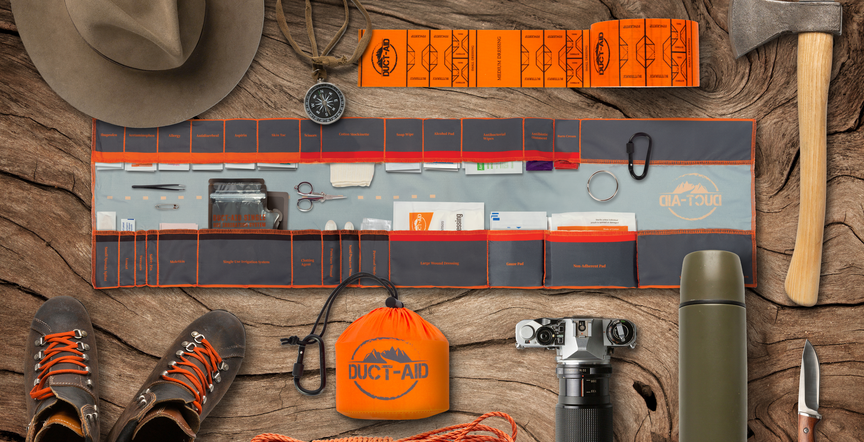 Outdoor survival kit with tools, first aid supplies, and camping gear on a wooden surface.