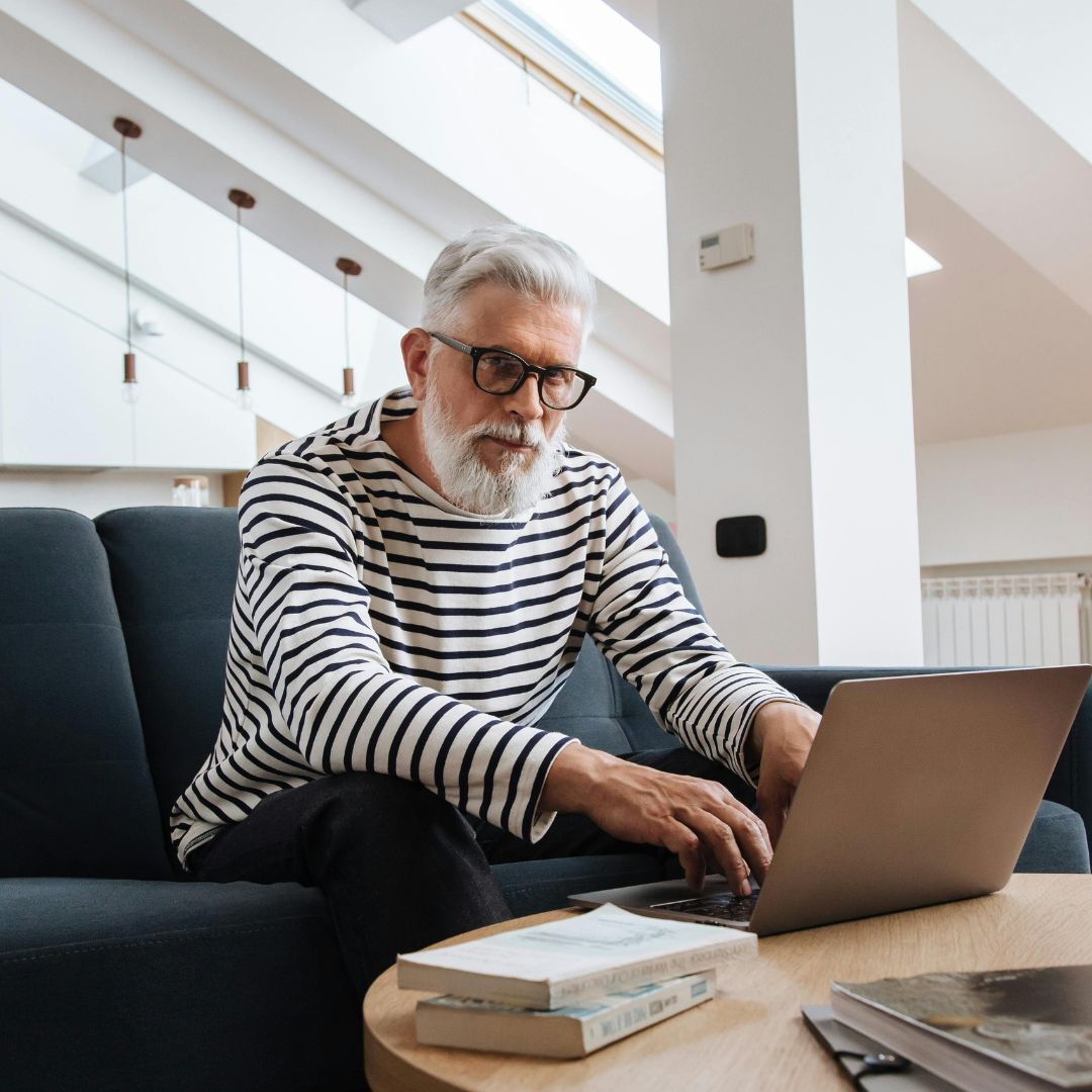 Person typing on a laptop while sitting in a modern living room.