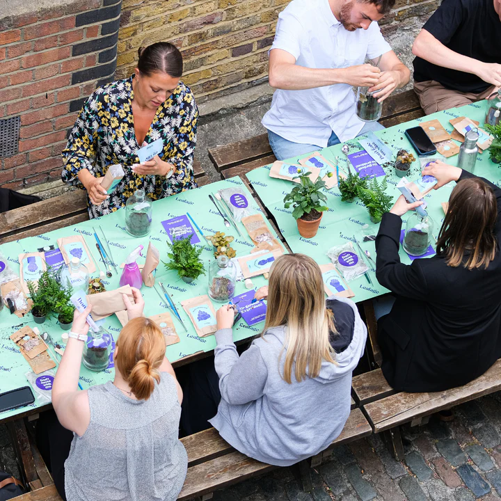 People sitting at a table engaged in a plant-related activity.