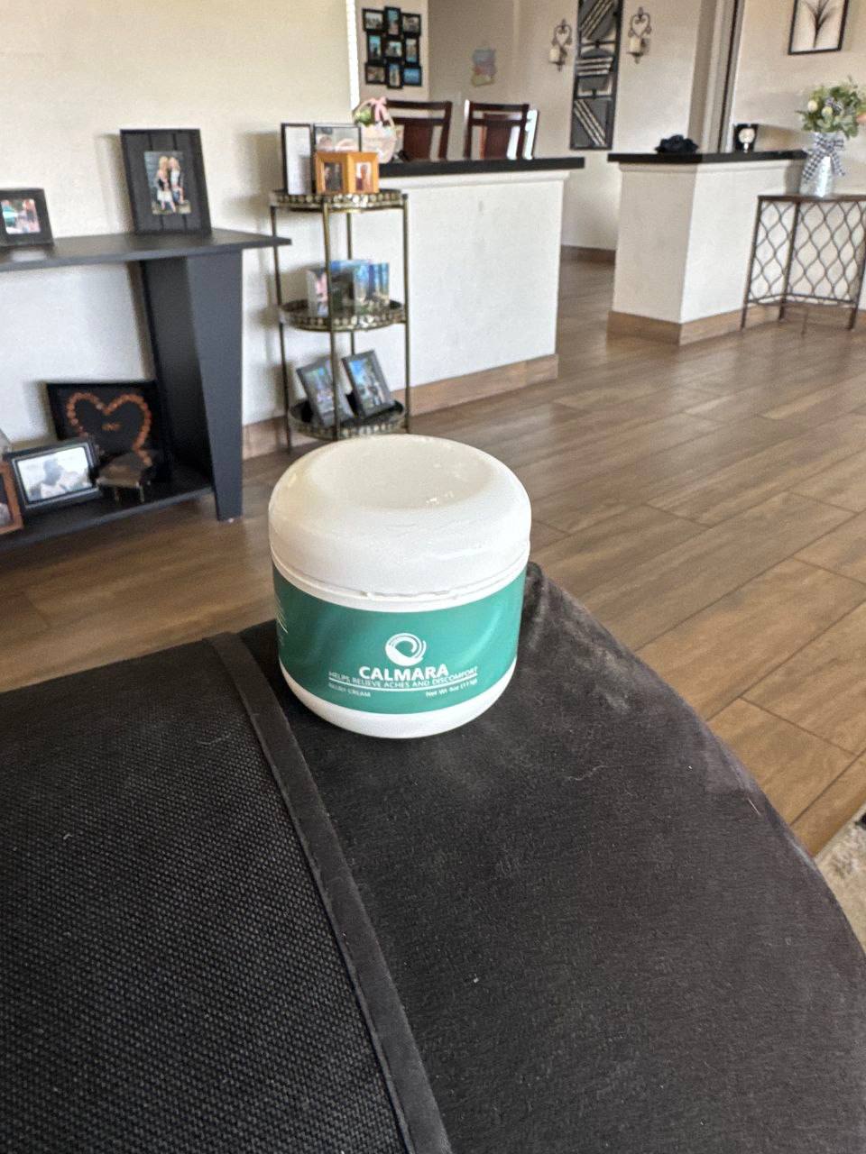 A jar of Calamara cream on a black surface in a living room.