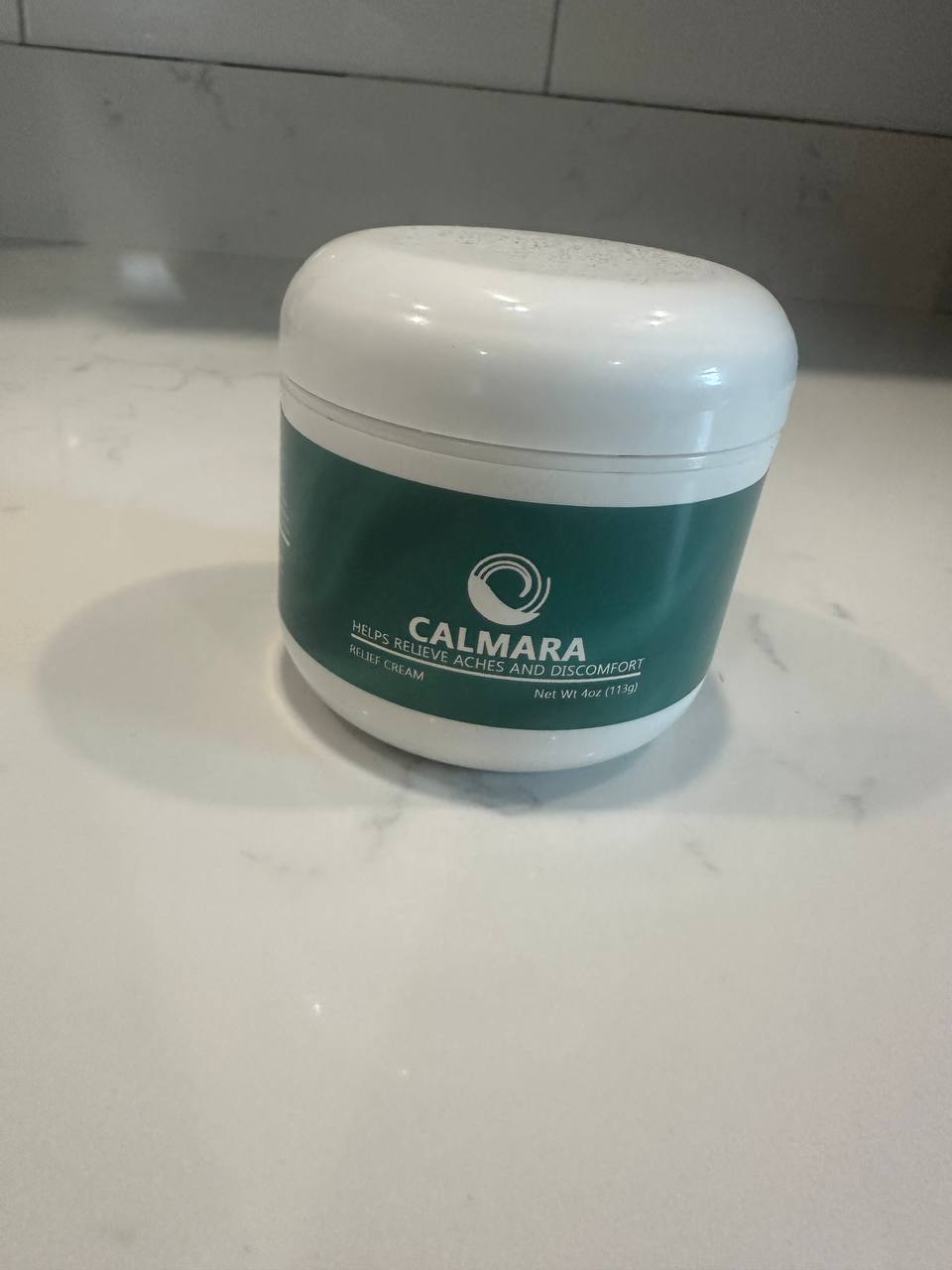 A jar of Calmara relief cream on a white surface.