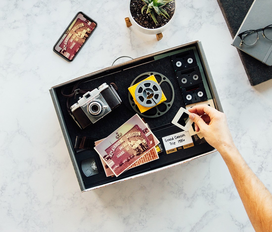 A vintage camera, photos, and film reels on a marble surface.