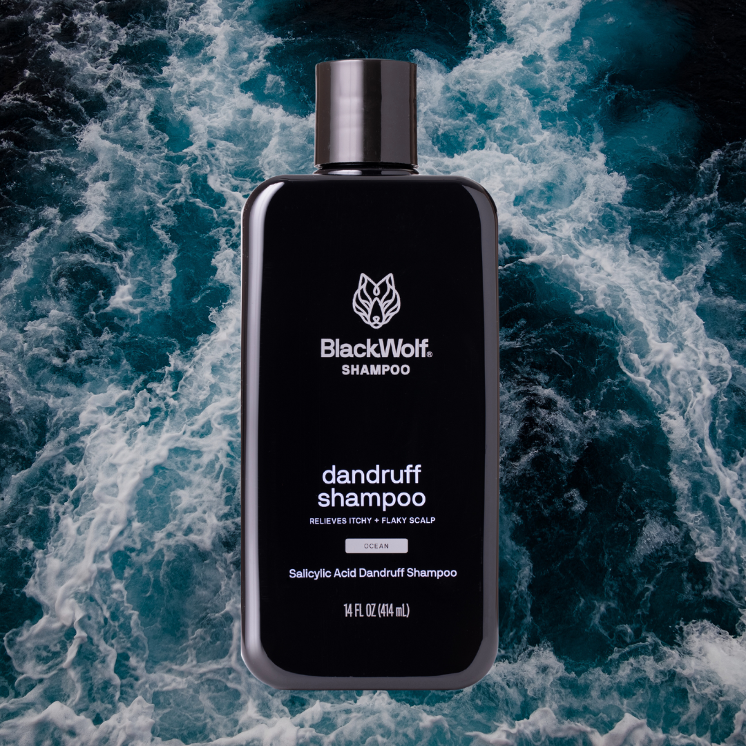 Black shampoo bottle labeled 'BlackWolf Dandruff Shampoo' against a background of ocean waves.