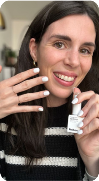 Person showing white nail polish on nails, holding a nail polish bottle.