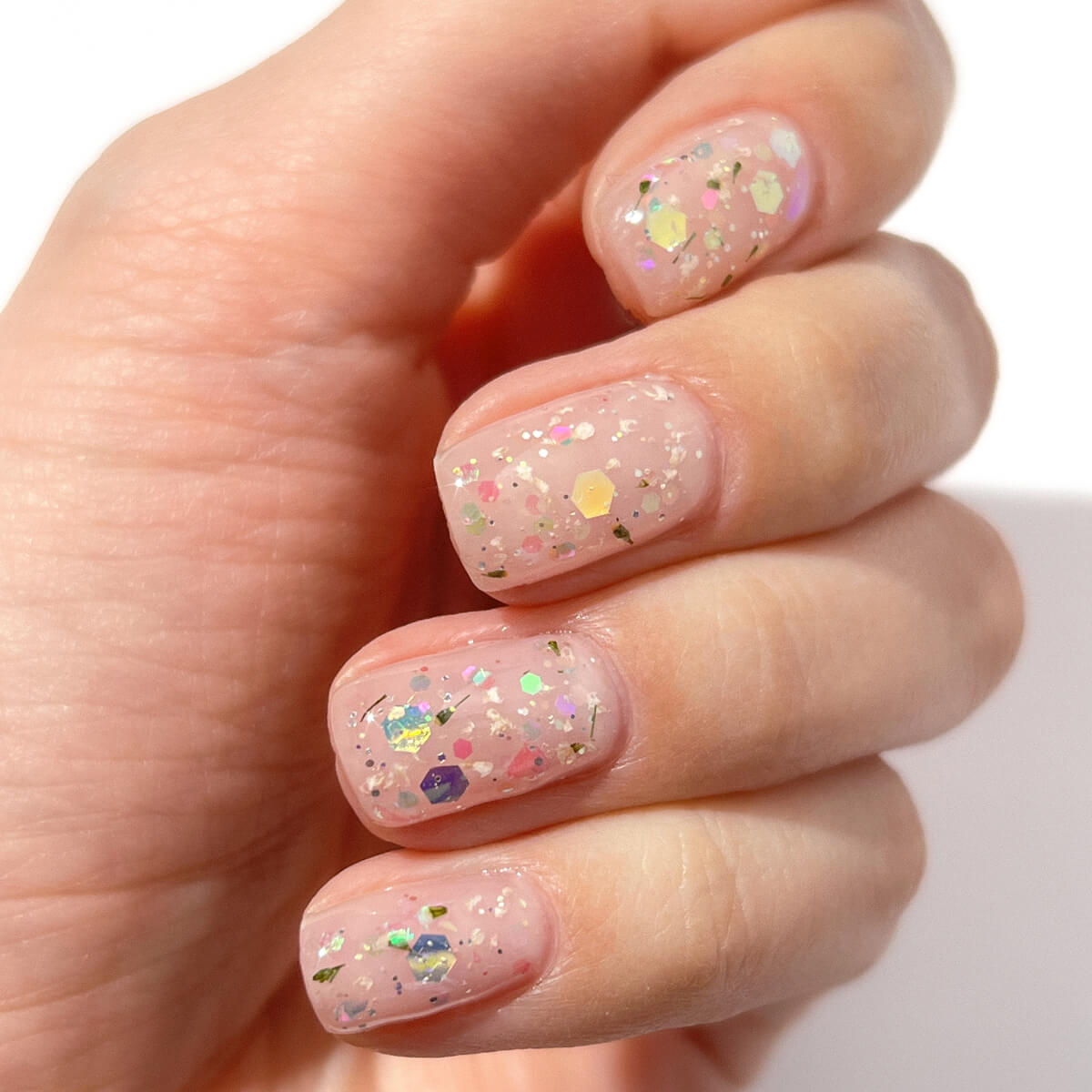 A hand with light pink nails featuring colorful glitter polish.