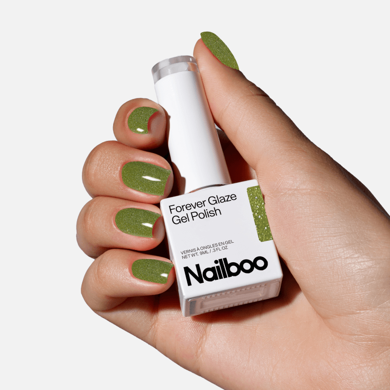 Hand holding a bottle of green gel nail polish with matching painted nails.
