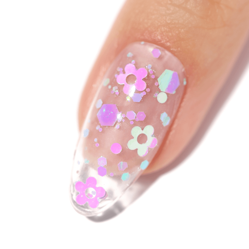Close-up of a fingernail with clear polish and colorful floral glitter.