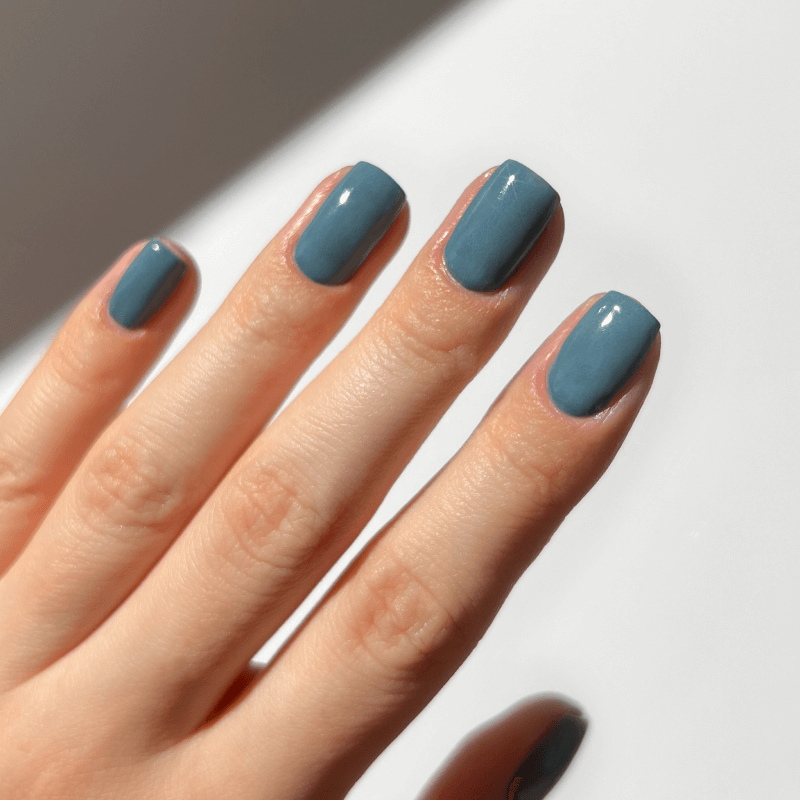 Hand with blue painted nails on a white background.