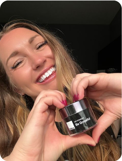 Person smiling, holding a jar labeled 'Be Grapeful' with hands forming a heart shape.