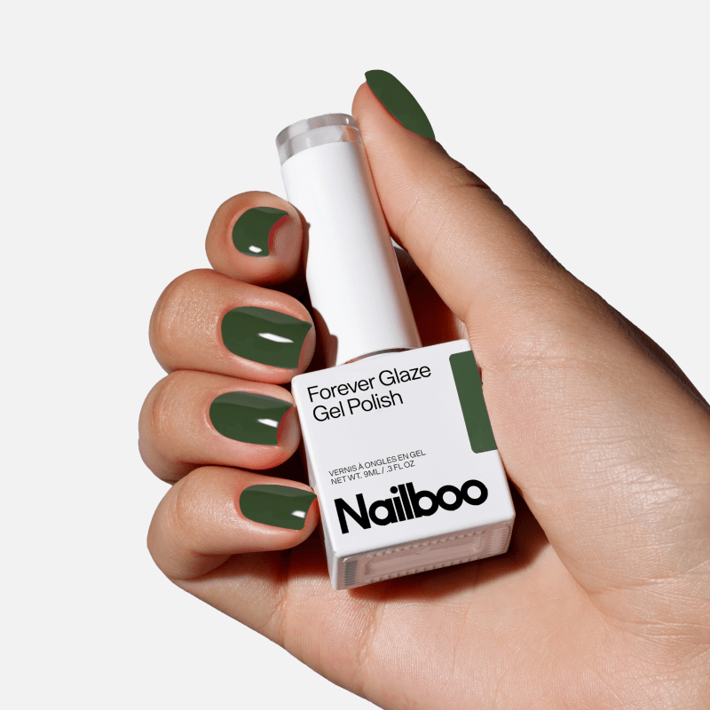 Hand holding a bottle of green gel nail polish with matching painted nails.