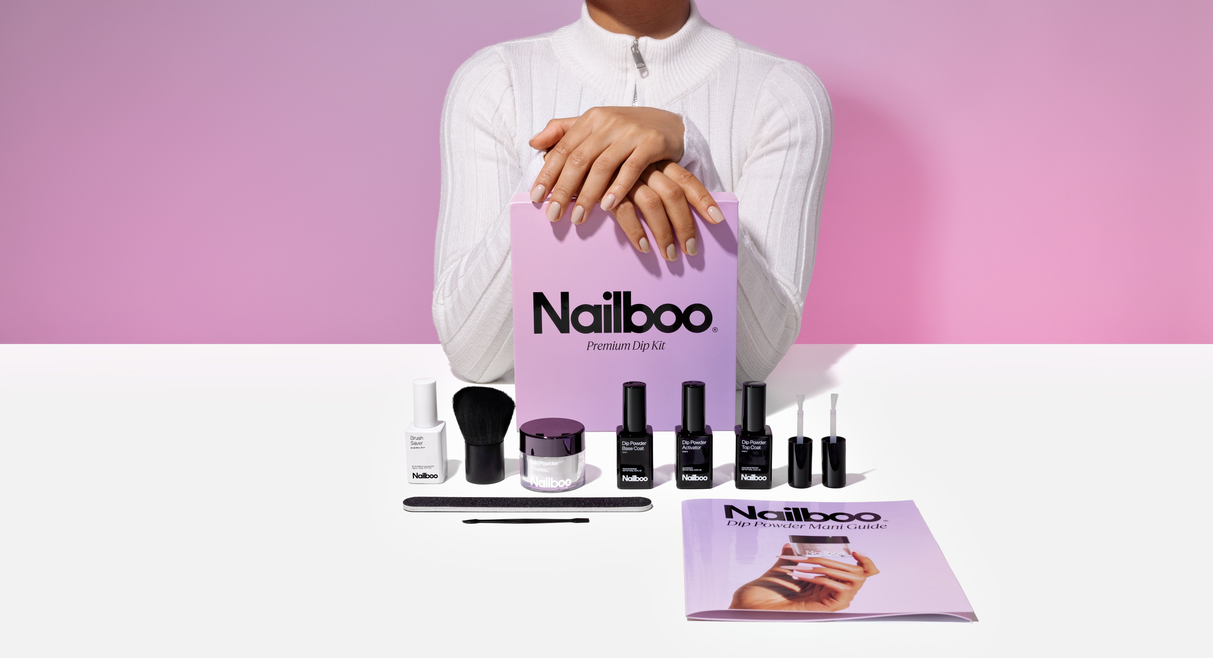 Nailboo dip kit with bottles, brush, and guide on a table.