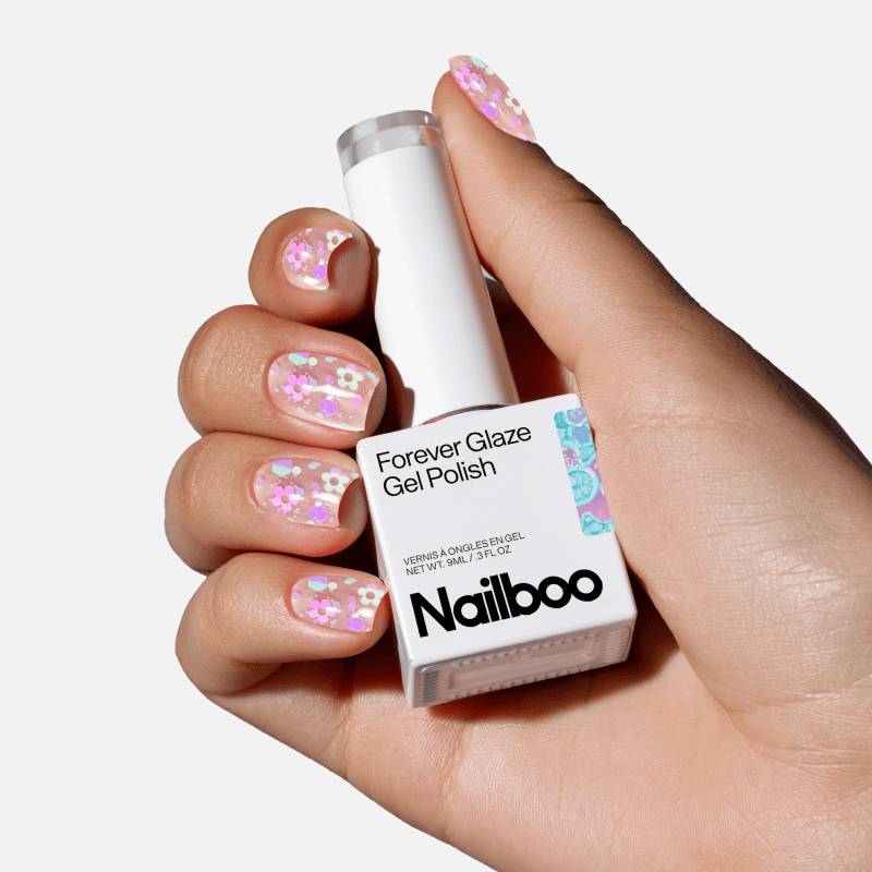 Hand holding a bottle of gel polish with floral nail art.