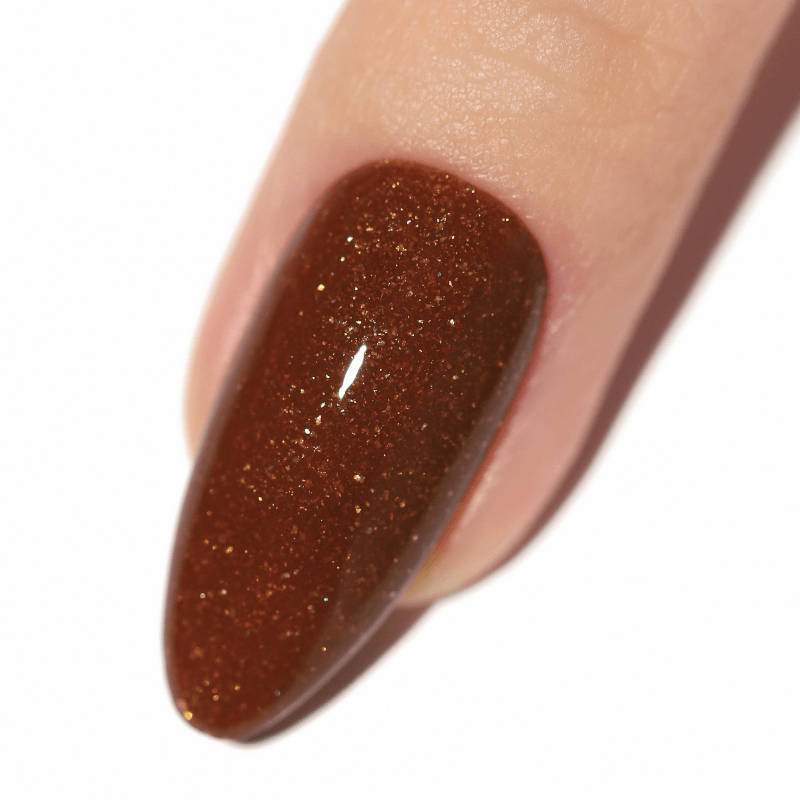 Close-up of a fingernail with brown glittery nail polish.