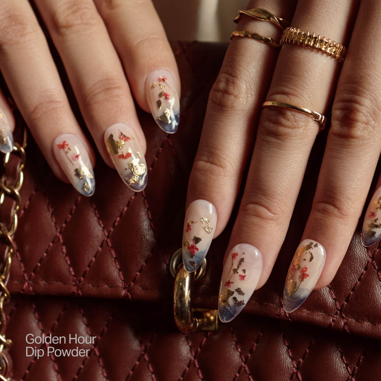 Hands with floral nail art on a quilted brown bag.
