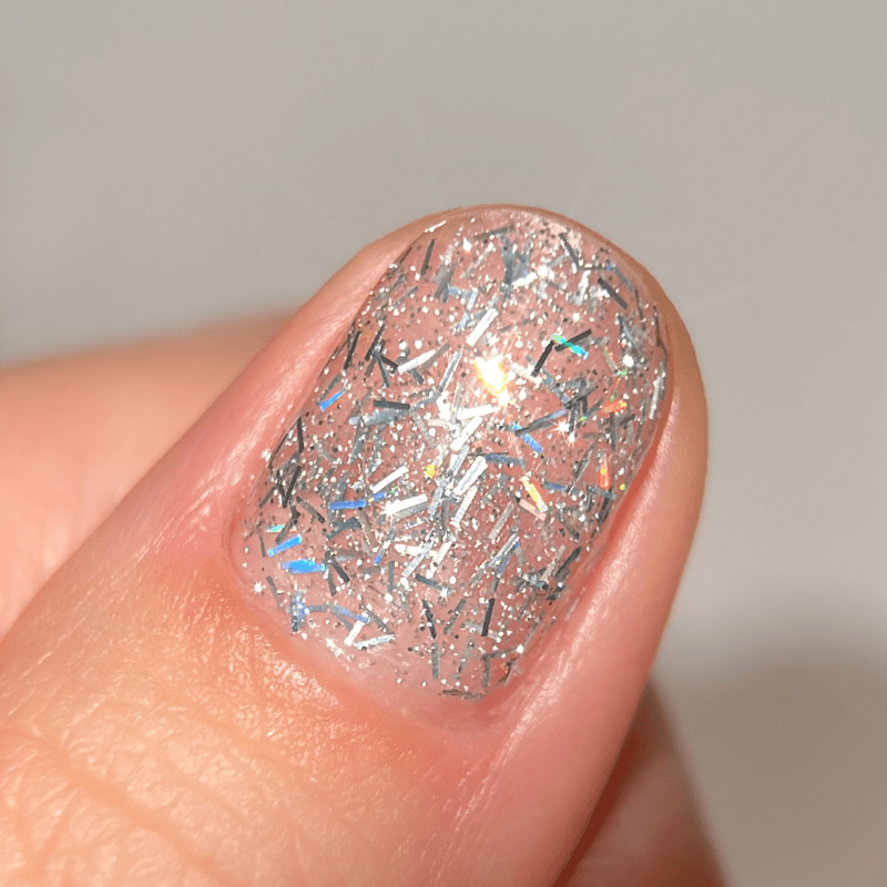 Close-up of a fingernail with silver glitter nail polish.