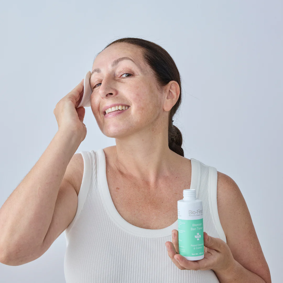 Person applying skincare product with a cotton pad, holding a bottle.