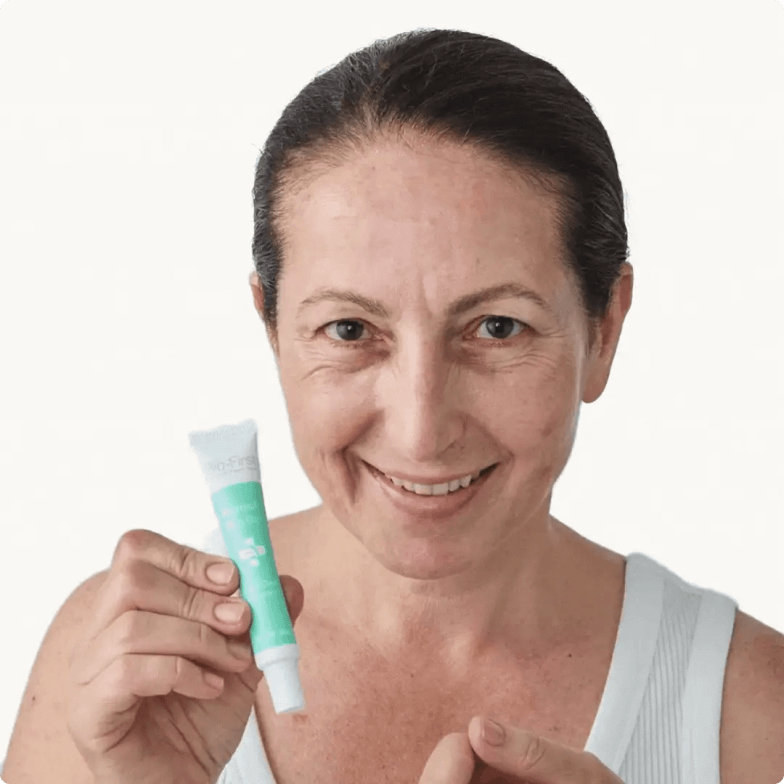 Person holding a tube of cream, smiling.