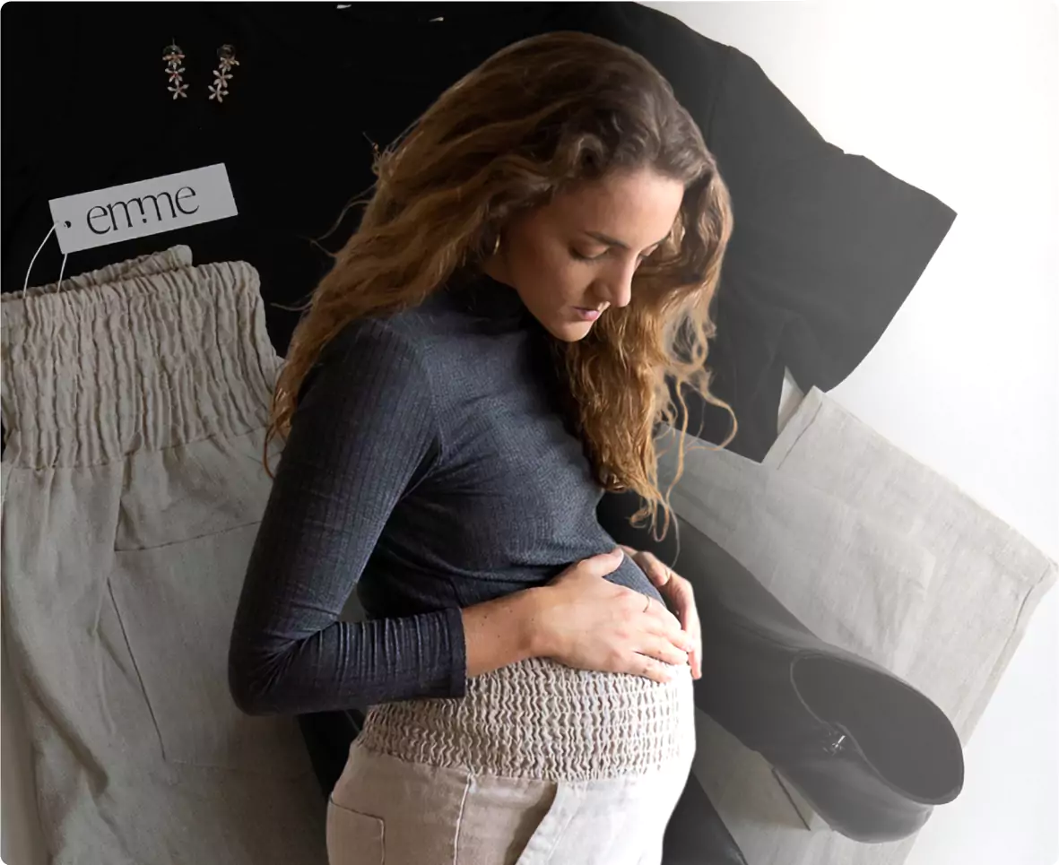 Pregnant woman in gray top, surrounded by clothing and accessories.