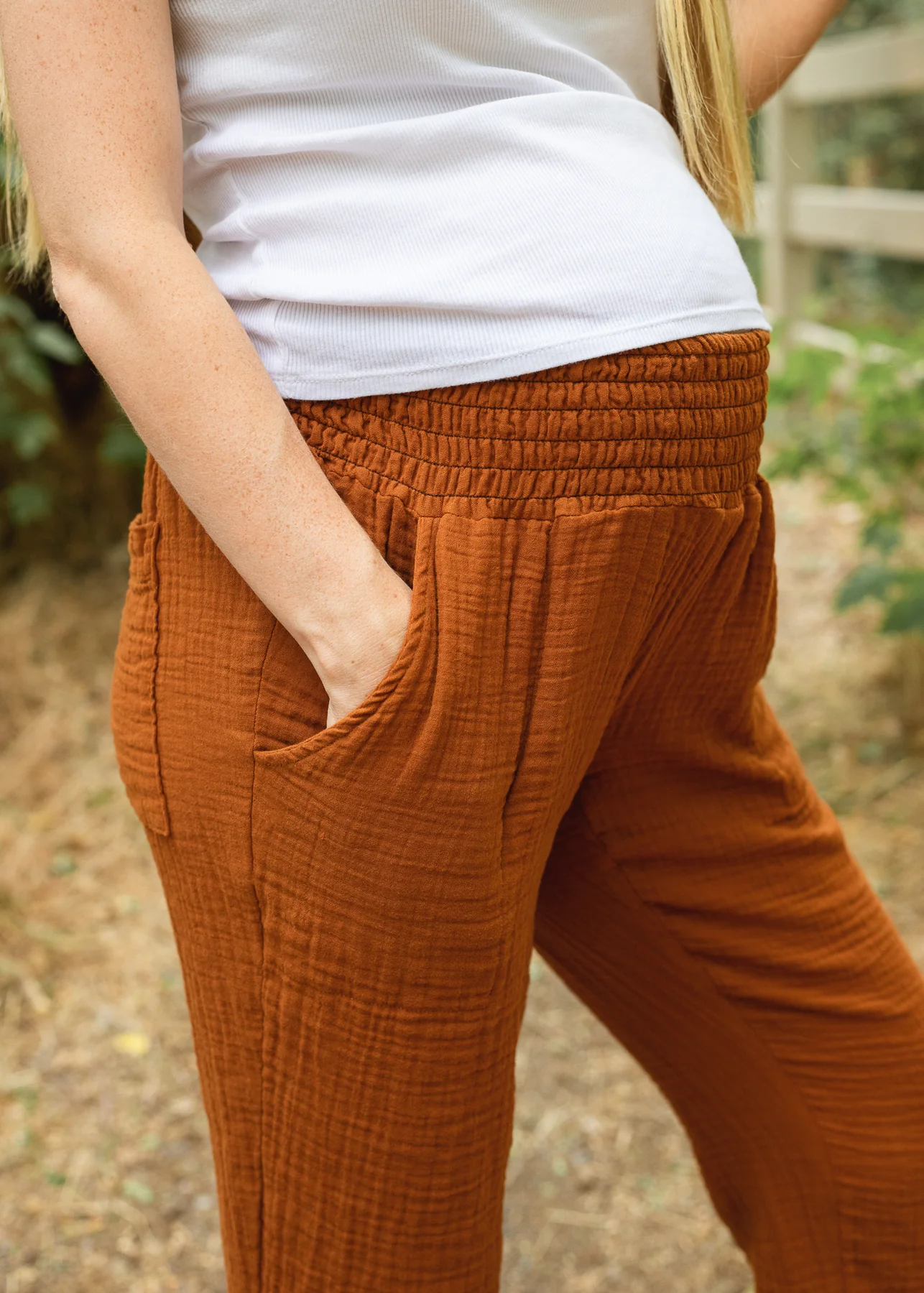 Person wearing rust-colored pants with hands in pockets.