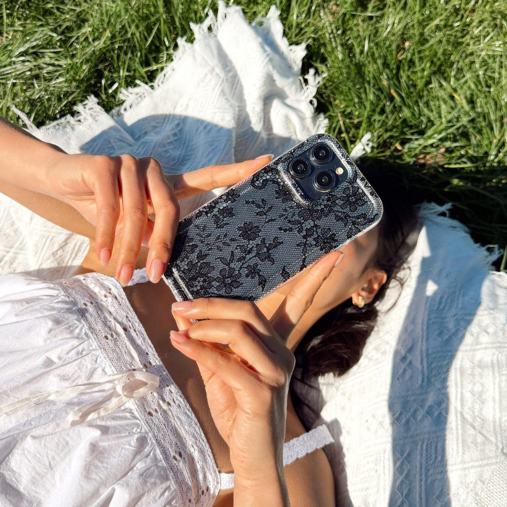 Two floral phone cases on a magazine cover next to a pink bag and a red drink.