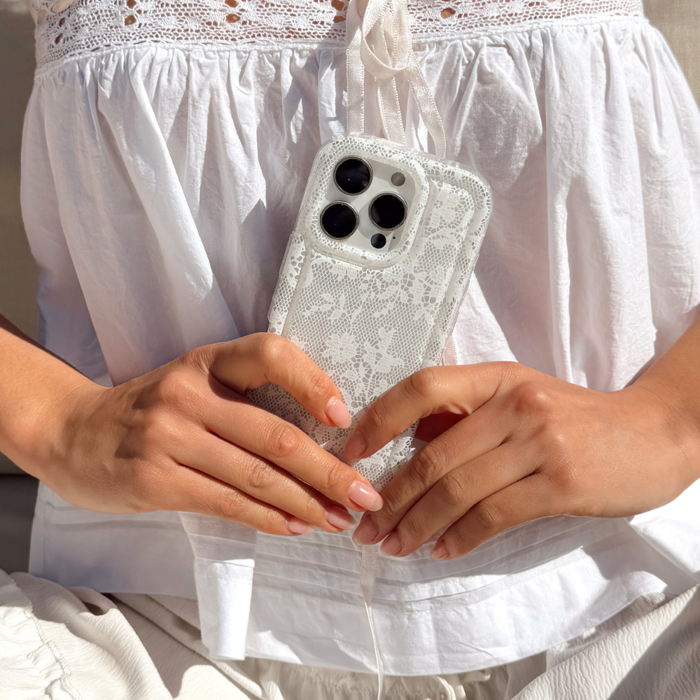 Two floral phone cases on a magazine cover next to a pink bag and a red drink.