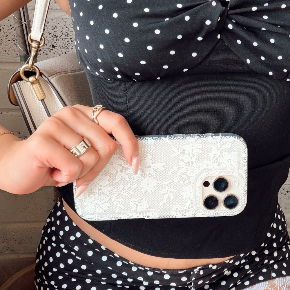 Two floral phone cases on a magazine cover next to a pink bag and a red drink.