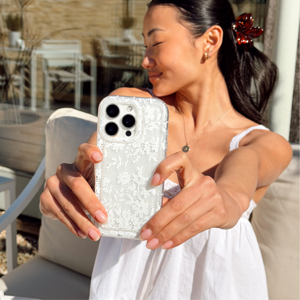 Two floral phone cases on a magazine cover next to a pink bag and a red drink.