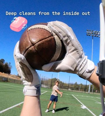First-person view of gloved hands holding a football on a field, with text and a soap graphic.