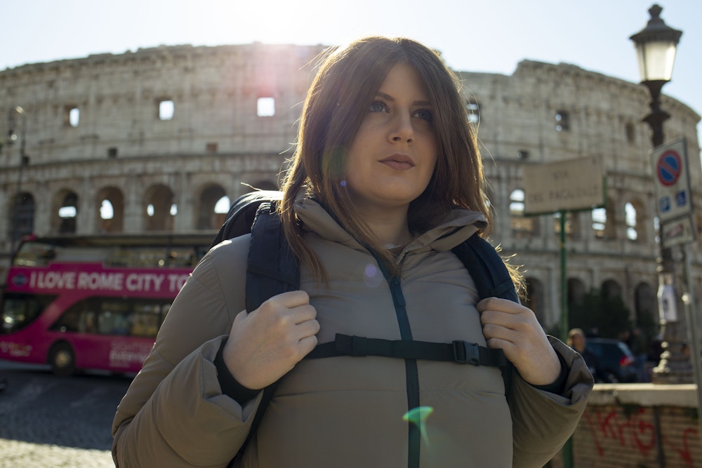 Person with backpack in front of the Colosseum, Rome.