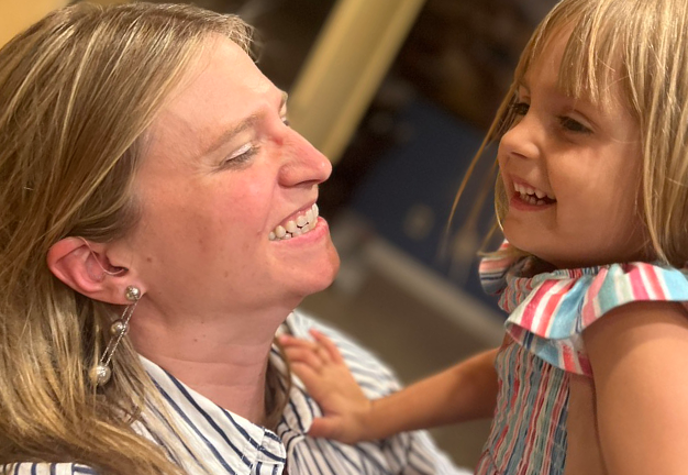 A woman smiling at a child, both laughing and looking at each other closely.