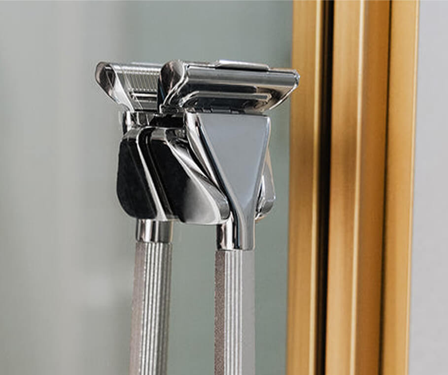 Close-up of two silver safety razors on a reflective surface.