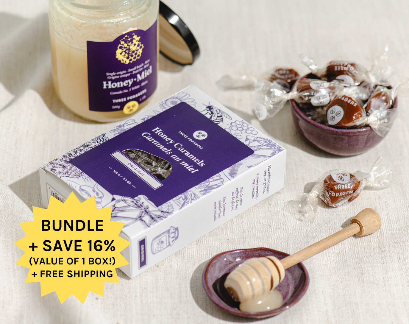 A jar of honey, a box of honey caramels, and a honey dipper on a cloth surface.