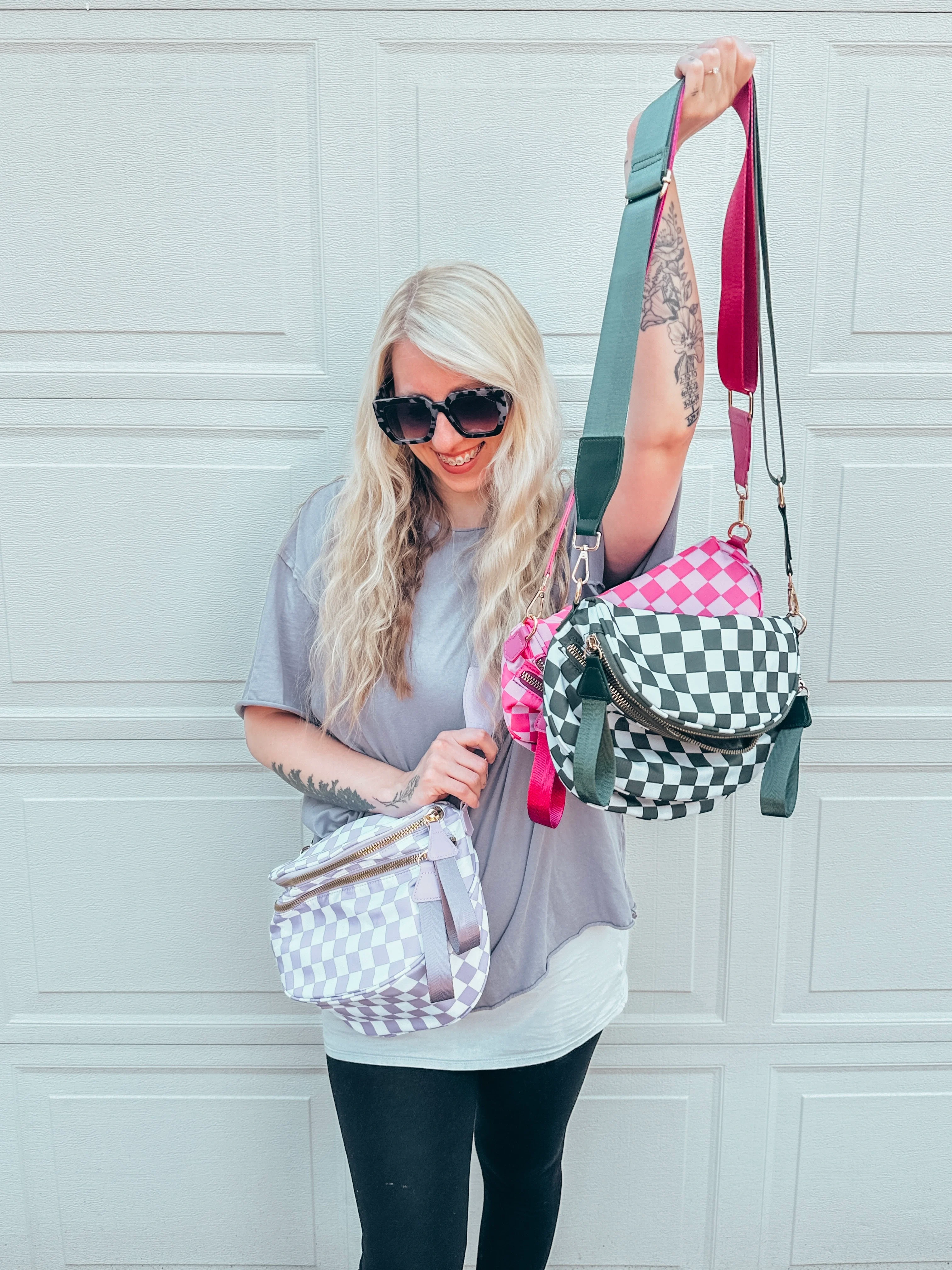Person holding three checkered bags in front of a garage door.