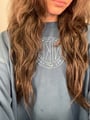 Person with long wavy hair wearing a blue sweatshirt.