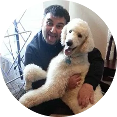 A person happily hugging a large, fluffy white dog indoors.