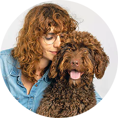 A woman happily hugging a large, fluffy dog outdoors.