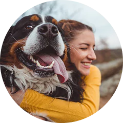 Woman hugging a large, happy dog outdoors.