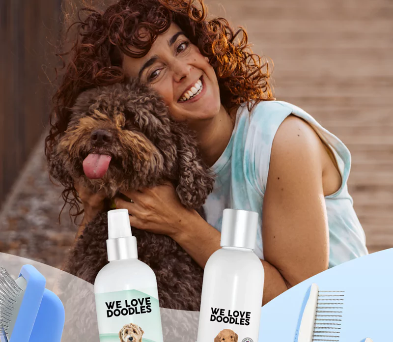 Smiling person hugging a fluffy dog with grooming products in the foreground.
