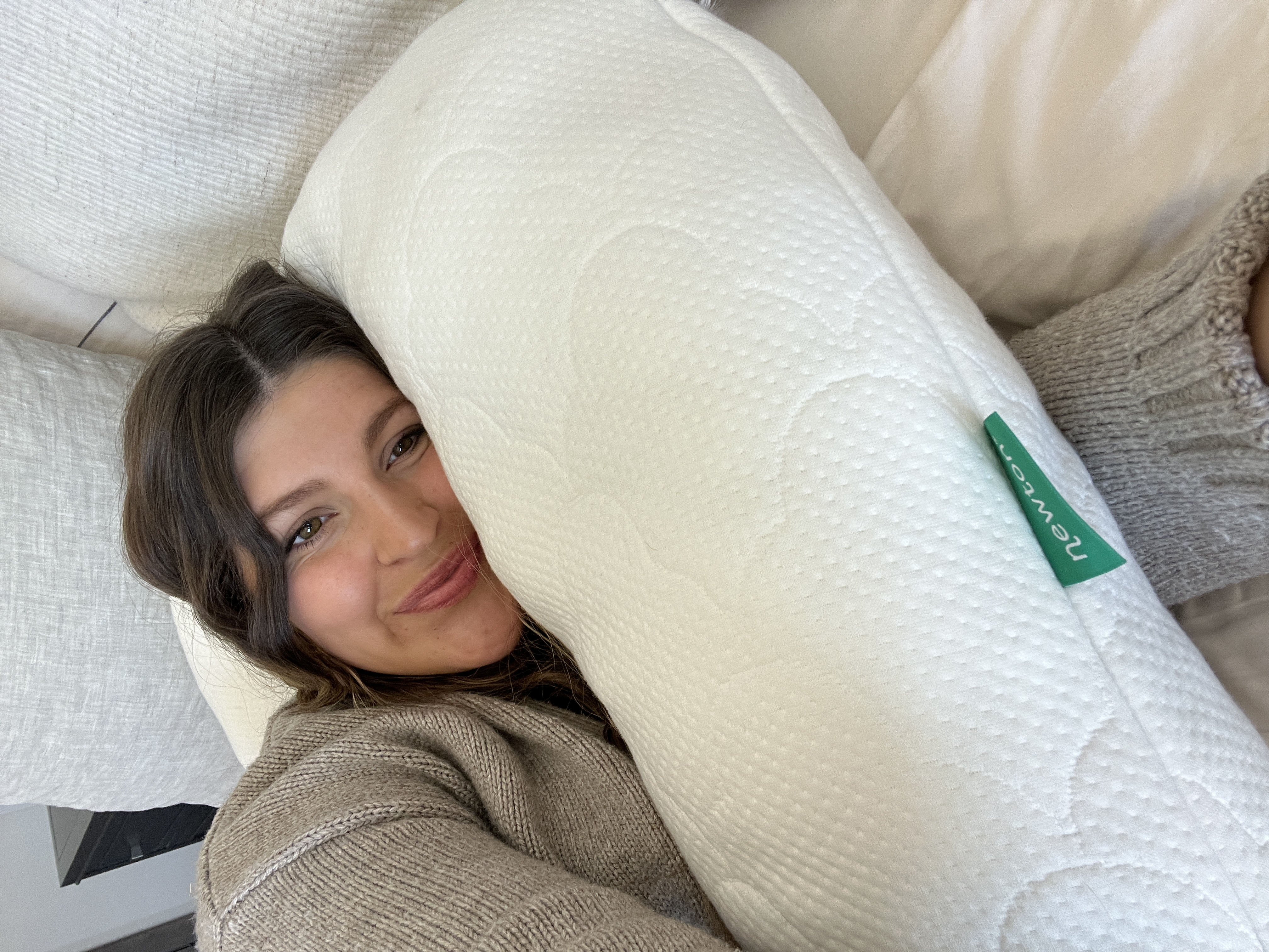 Woman smiling while cozying up to The Newton Pillow
