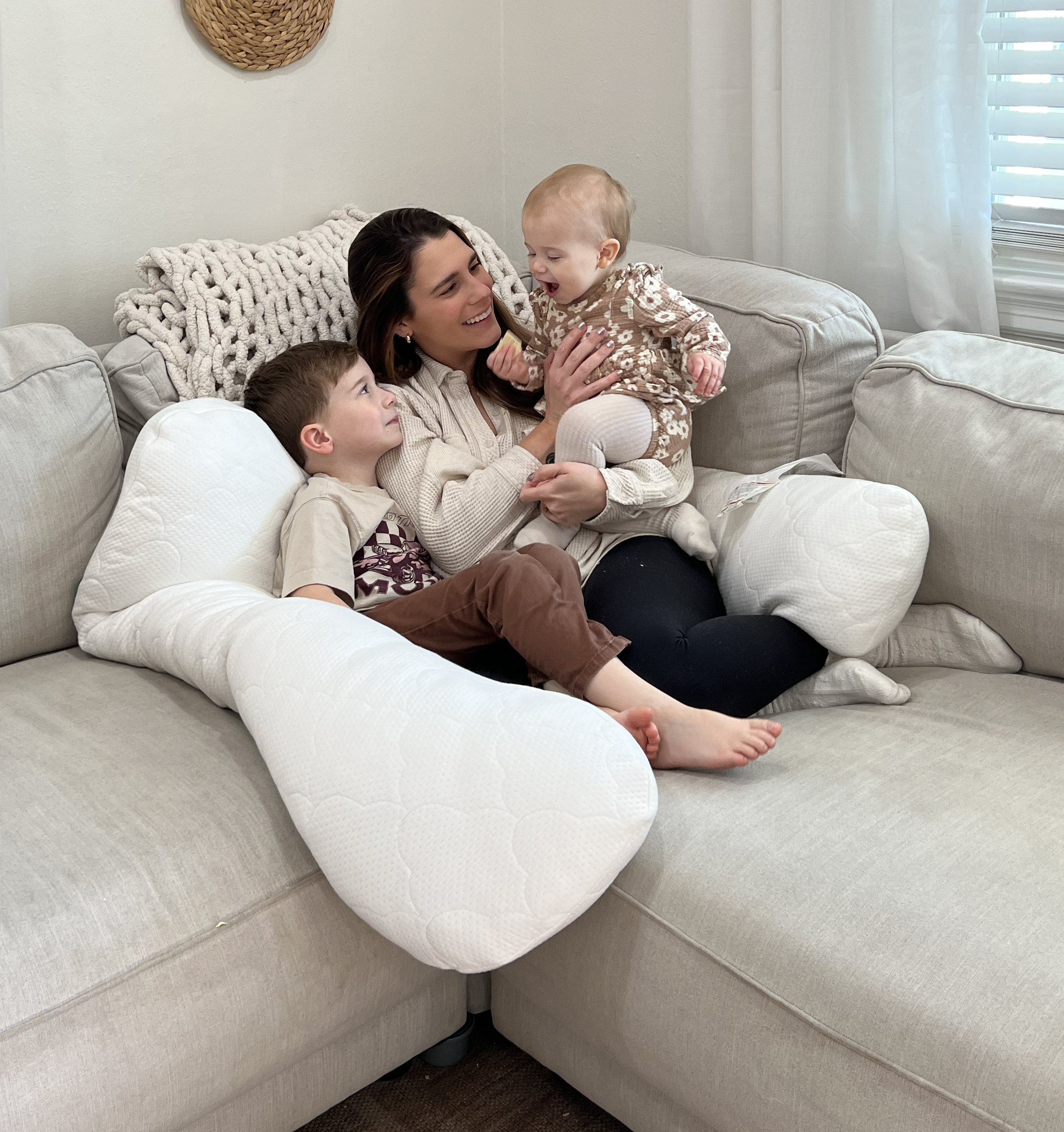Woman and two young children snuggling on a couch with The Newton Pillow