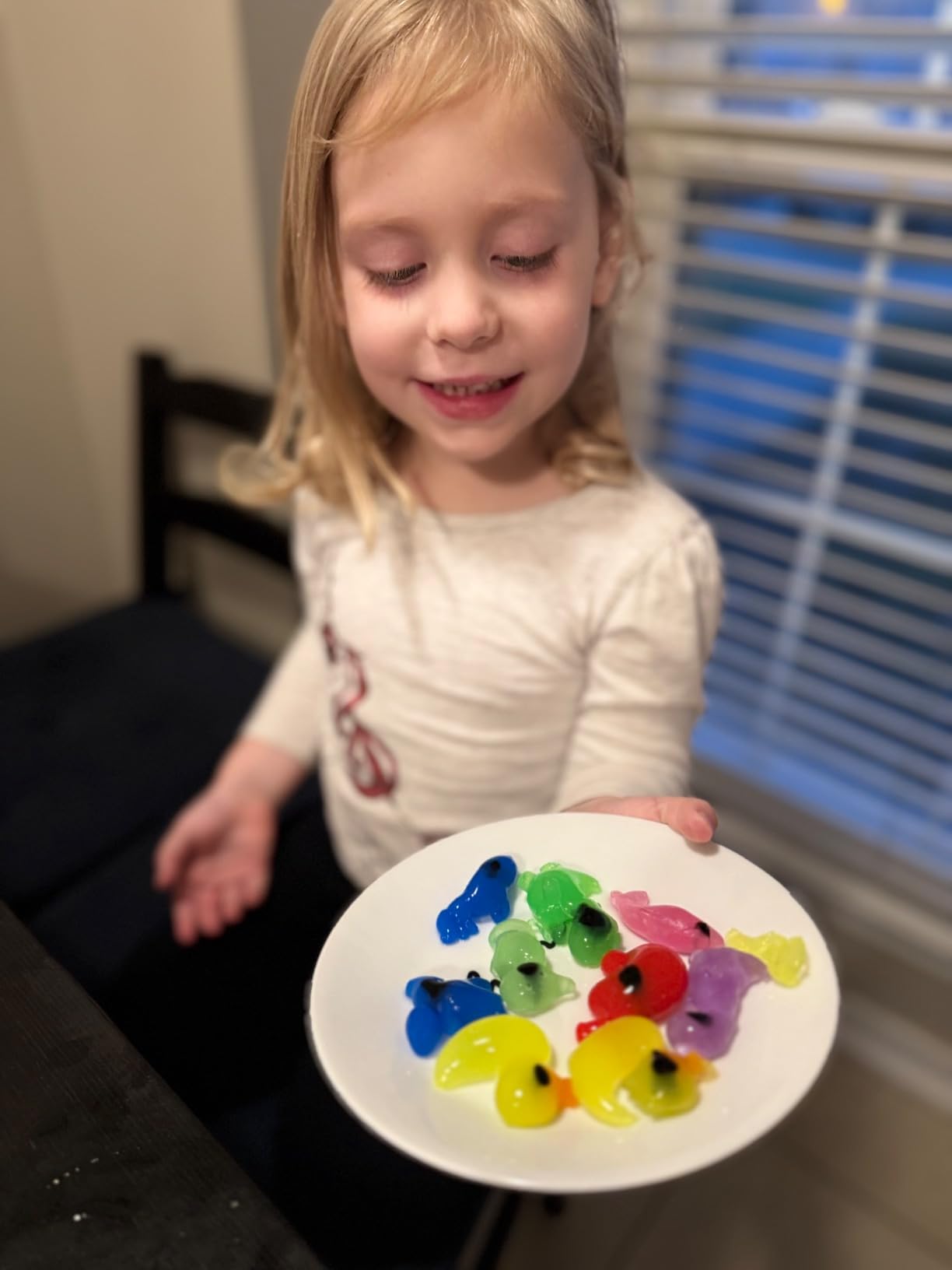 Child holding a plate with colorful jelly animal shapes.