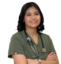 Person in green scrubs with a stethoscope, smiling and arms crossed.